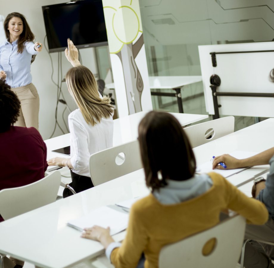 Group of young students rising hands to answer the question during the workshop training